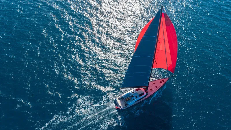 Caiarossa Yacht Photos Pics Aerial view of 2009 Shipman 72 sailboat with vibrant red and blue sails on open sea.