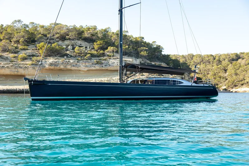 Caiarossa Yacht Photos Pics Sleek 2009 Shipman 72 yacht anchored in clear turquoise waters near rocky coastline.