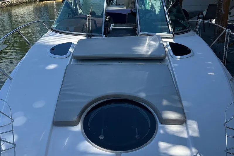 Panacea Yacht Photos Pics 2015 Regal 32 Express boat deck with sunpad and hatch, docked by the water.