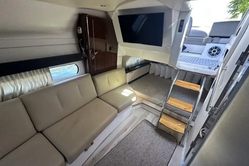 Panacea Yacht Photos Pics 2015 Regal 32 Express interior with beige seating, TV, and wooden steps.