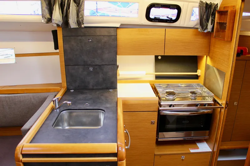 Selkie Yacht Photos Pics Interior of 2015 Jeanneau Sun Odyssey 349 yacht, featuring a compact kitchen with sink and stove.