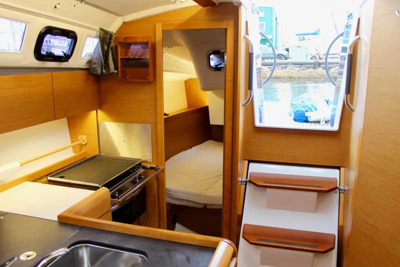 Selkie Yacht Photos Pics Interior of 2015 Jeanneau Sun Odyssey 349 sailboat, featuring kitchen and cozy cabin space.