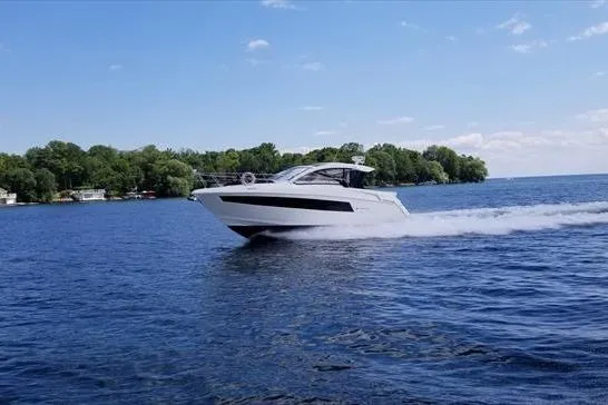  Yacht Photos Pics 2019 Cruisers Yachts 390 Express Coupe cruising on a serene lake under a clear sky.