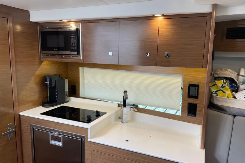  Yacht Photos Pics 2019 Cruisers Yachts 390 Express Coupe kitchen with modern appliances and sleek wood cabinetry.
