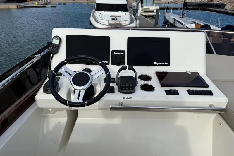  Yacht Photos Pics Control panel of a 2020 Prestige 520 yacht with steering wheel and navigation screens.