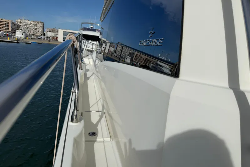  Yacht Photos Pics 2020 Prestige 520 yacht docked at marina, reflecting cityscape on water.