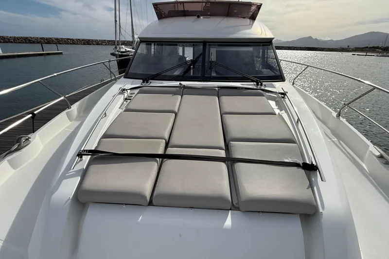  Yacht Photos Pics 2020 Prestige 520 yacht with cushioned sunbathing area, docked in a serene marina.