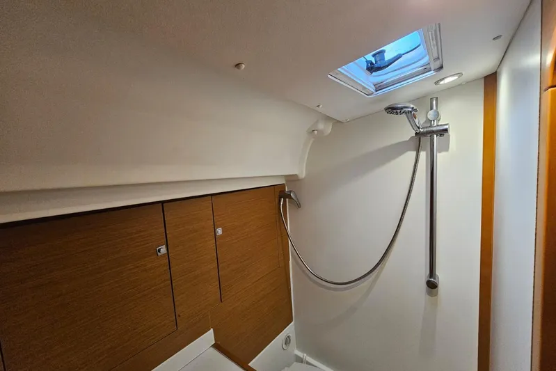 Urkab Yacht Photos Pics Bathroom interior of 2018 Jeanneau Sun Odyssey 449 yacht with shower and wooden cabinets.