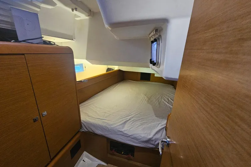Urkab Yacht Photos Pics Interior cabin of 2018 Jeanneau Sun Odyssey 449 sailboat, featuring a cozy bed and wooden cabinetry.