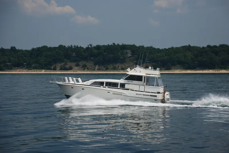  Yacht Photos Pics 1986 Bertram 46 Flybridge Motor Yacht cruising on calm waters near a forested shoreline.