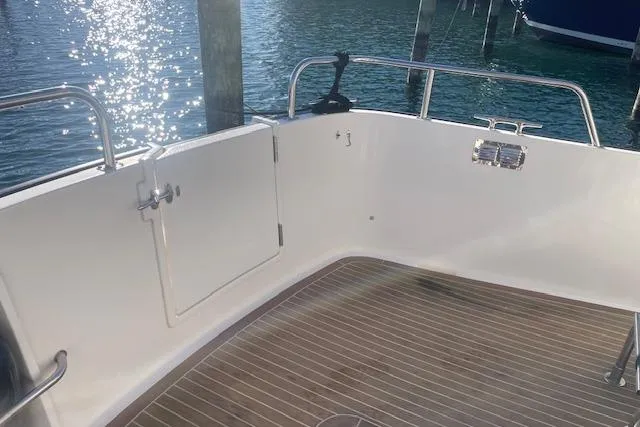  Yacht Photos Pics 2006 Nordic Tug 42 boat deck with wooden flooring and railing, docked by shimmering water.