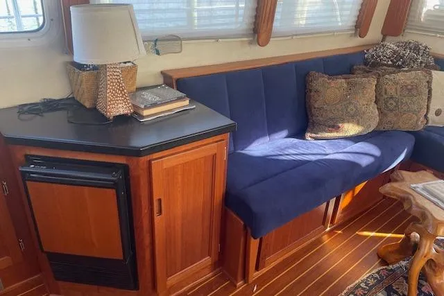  Yacht Photos Pics Interior of 2006 Nordic Tug 42 with blue seating, wooden cabinetry, and decorative pillows.