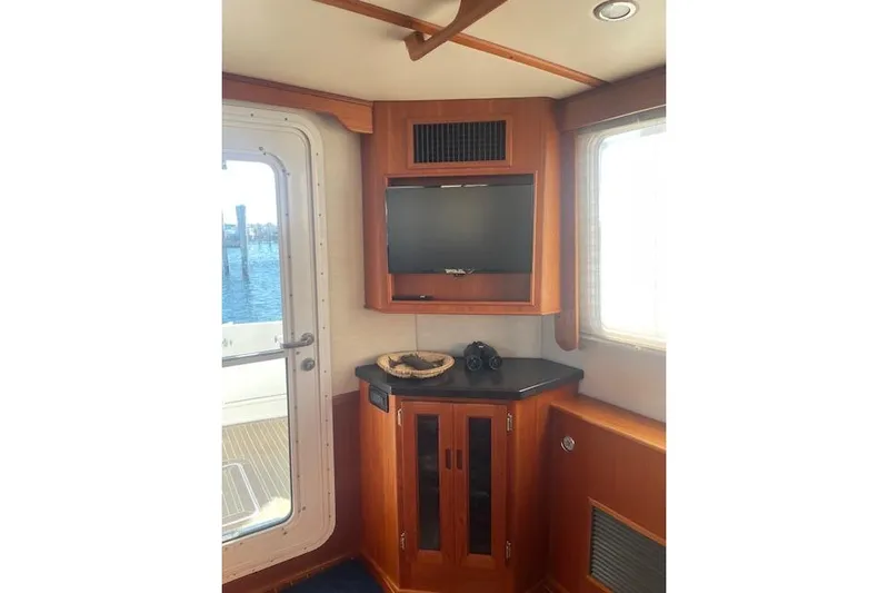  Yacht Photos Pics Interior of 2006 Nordic Tug 42 with TV, cabinet, and window view.