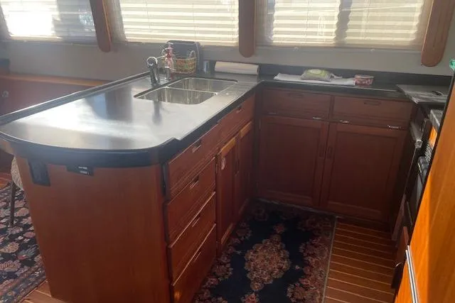  Yacht Photos Pics 2006 Nordic Tug 42 kitchen with wooden cabinets, black countertop, and stainless steel sink.