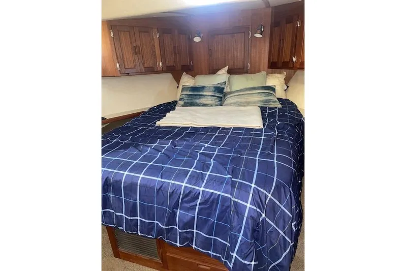  Yacht Photos Pics Cozy bedroom in 2006 Nordic Tug 42 with blue checkered bedding and wooden cabinets.