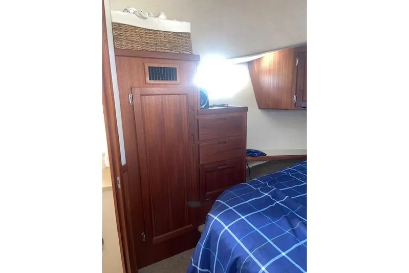  Yacht Photos Pics Cozy cabin interior of 2006 Nordic Tug 42 with wooden cabinetry and blue bedding.