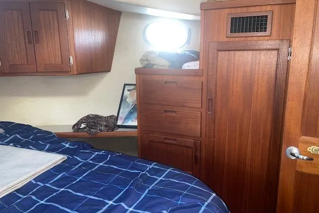  Yacht Photos Pics Cozy cabin interior of 2006 Nordic Tug 42 with wooden cabinetry and blue bedding.