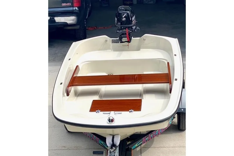  Yacht Photos Pics Small boat with wooden seats and outboard motor, parked on a trailer.