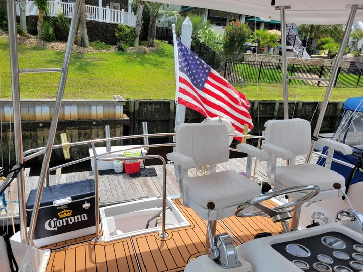 The Dog Patch Yacht Photos Pics 1990 Ocean Yachts 48 Super Sport with American flag, docked, featuring white seating and wooden deck.