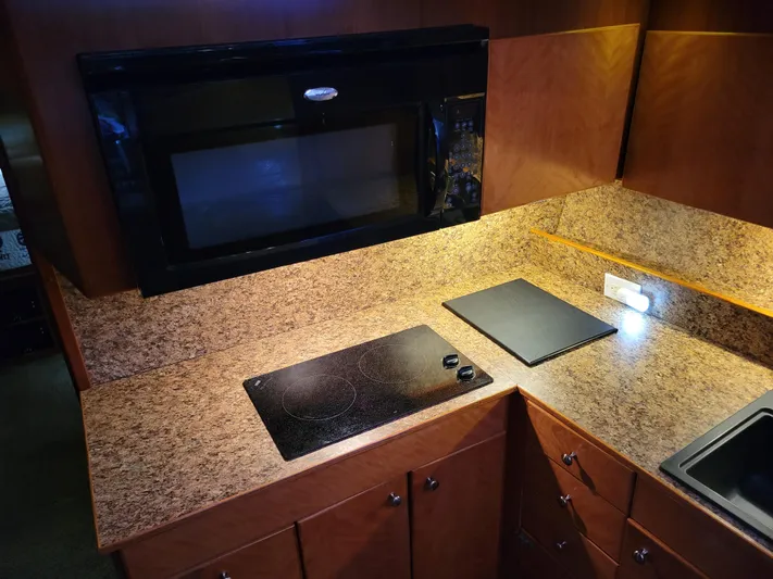 The Dog Patch Yacht Photos Pics 1990 Ocean Yachts 48 Super Sport kitchen with stove, microwave, and wood cabinetry.