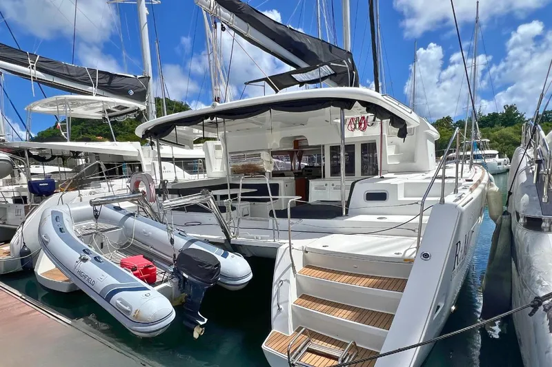 Take It Easy Yacht Photos Pics 2018 Lagoon 450 F catamaran docked with inflatable dinghy, clear skies, and marina backdrop.
