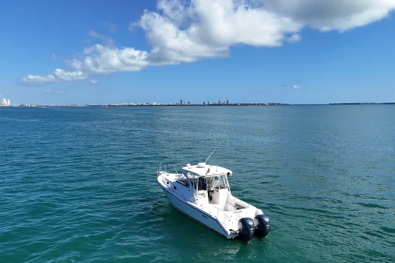  Yacht Photos Pics 2004 Pursuit 3370 Offshore boat on calm ocean with city skyline in background.