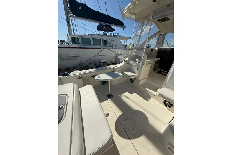  Yacht Photos Pics 2004 Pursuit 3370 Offshore boat interior with seating and table, docked beside another vessel.