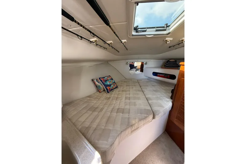  Yacht Photos Pics Cozy cabin interior of 2004 Pursuit 3370 Offshore boat with bedding and fishing rods.