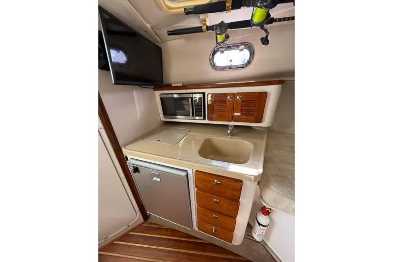  Yacht Photos Pics 2004 Pursuit 3370 Offshore boat interior with kitchenette, sink, microwave, and TV.