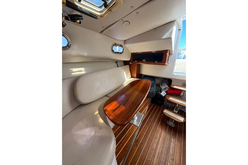  Yacht Photos Pics Interior of 2004 Pursuit 3370 Offshore boat with wooden table and seating area.