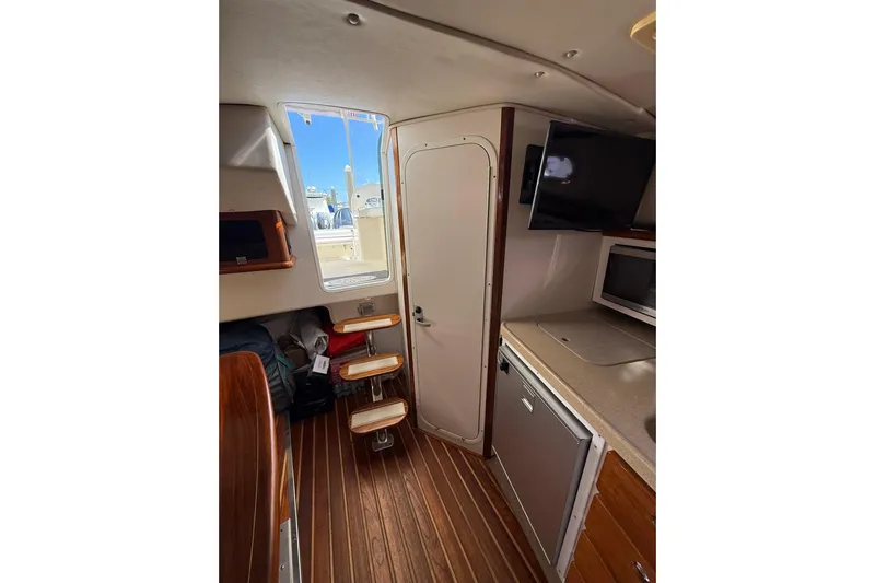  Yacht Photos Pics 2004 Pursuit 3370 Offshore cabin interior with wooden flooring and compact kitchen area.