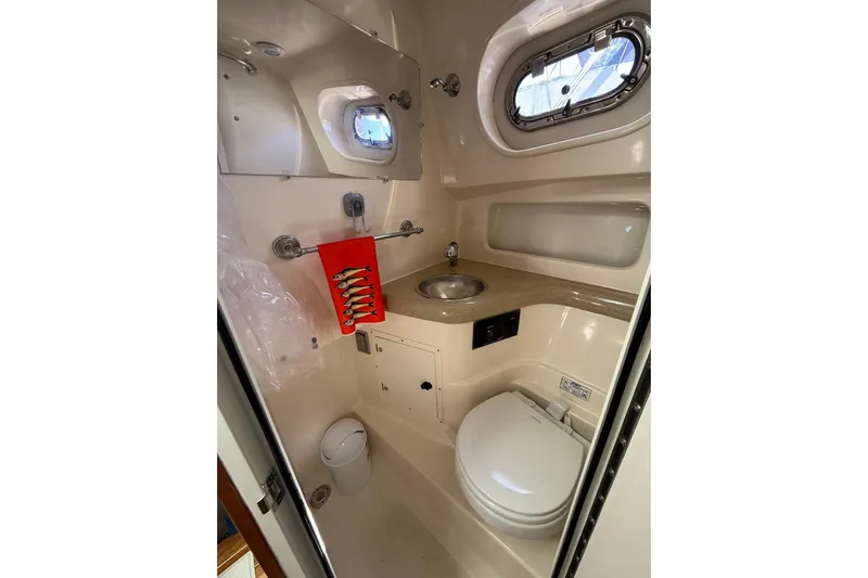  Yacht Photos Pics 2004 Pursuit 3370 Offshore boat bathroom with sink, toilet, and porthole window.