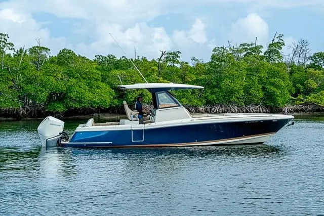  Yacht Photos Pics 2019 Chris-Craft Catalina 30 boat cruising on calm water near lush greenery.