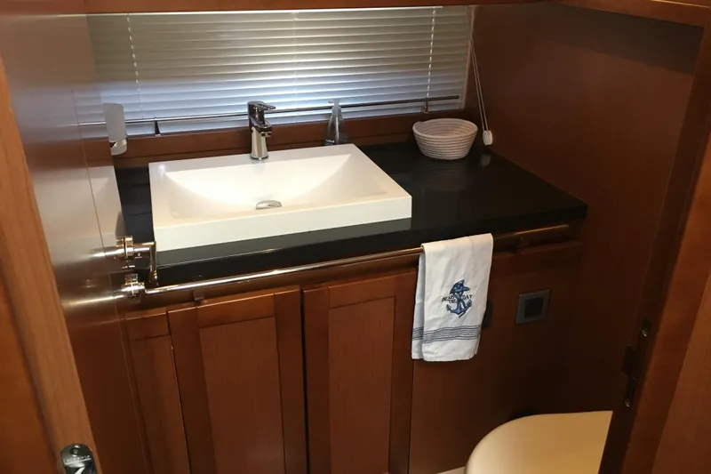  Yacht Photos Pics Bathroom interior of 2018 Beneteau Swift Trawler 50 with modern sink and wooden cabinetry.
