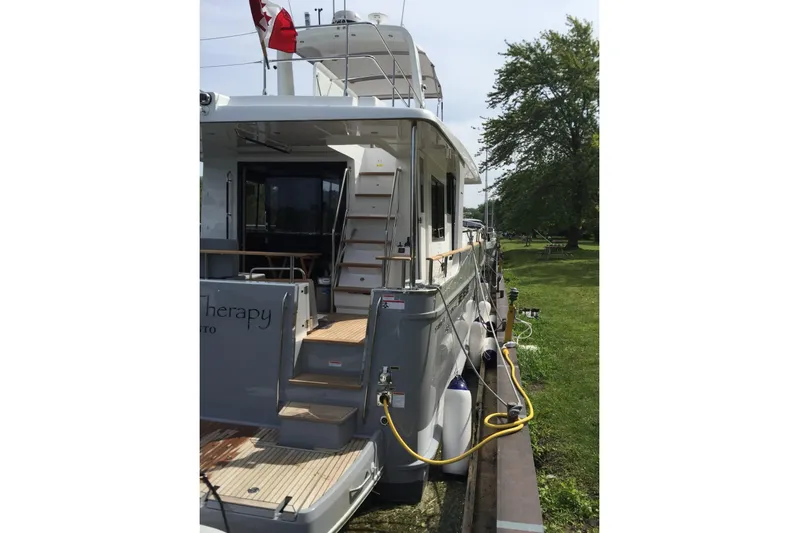  Yacht Photos Pics 2018 Beneteau Swift Trawler 50 docked, rear view with Canadian flag, lush greenery nearby.