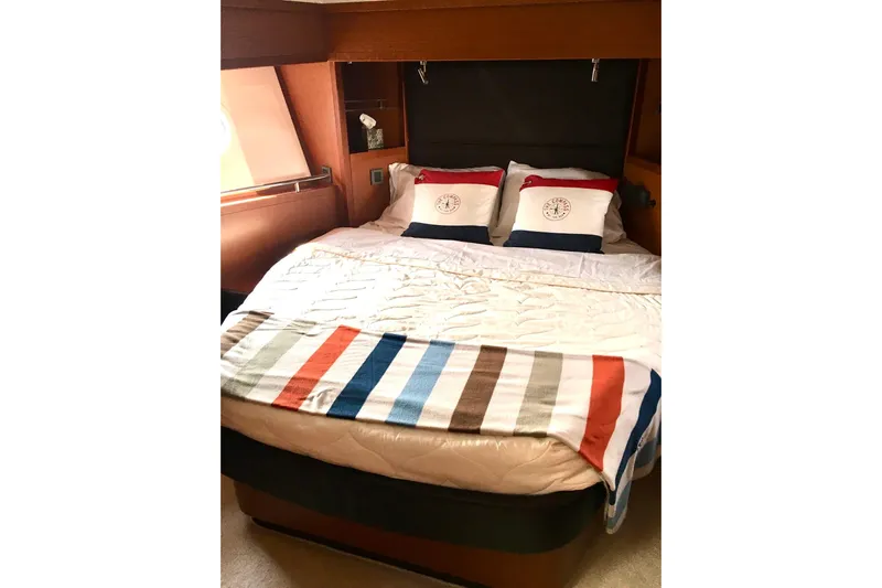  Yacht Photos Pics Cozy bedroom in 2018 Beneteau Swift Trawler 50 with striped blanket and nautical pillows.
