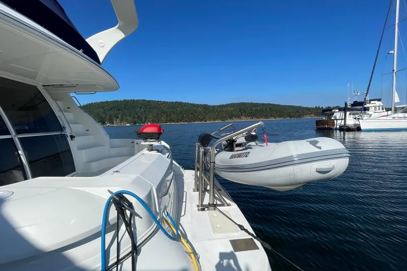  Yacht Photos Pics 2001 Cruisers Yachts 5000 Pilothouse with dinghy, docked in scenic marina.