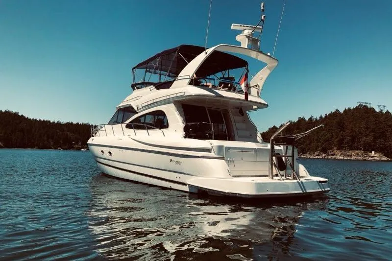  Yacht Photos Pics 2001 Cruisers Yachts 5000 Pilothouse on serene water with forested shoreline.