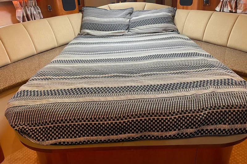  Yacht Photos Pics Luxurious bed in 2001 Cruisers Yachts 5000 Pilothouse cabin, featuring striped bedding.