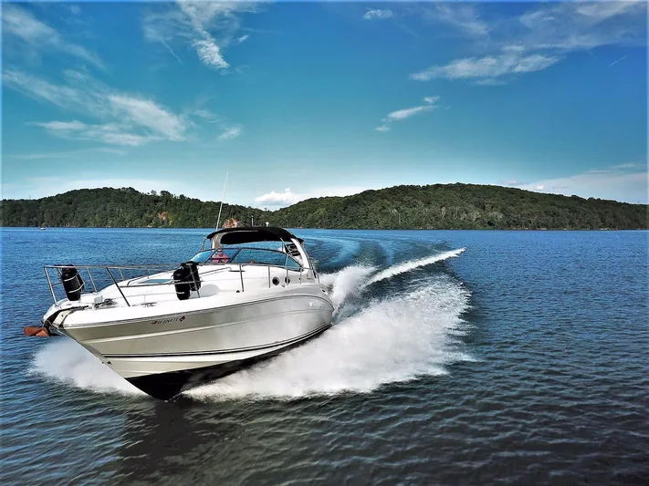  Yacht Photos Pics 2005 Sea Ray 360 Sundancer cruising on a lake with scenic hills in the background.