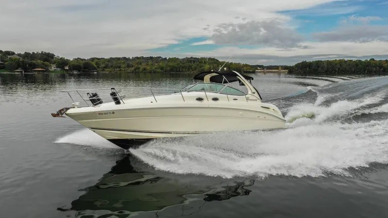  Yacht Photos Pics 2005 Sea Ray 360 Sundancer cruising on a serene lake under a partly cloudy sky.