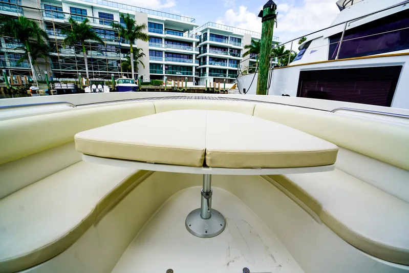 Tender Offer Yacht Photos Pics 2008 Chris-Craft Catalina 29 boat interior with cushioned seating and table, docked near modern buildings.