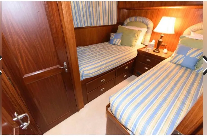  Yacht Photos Pics 1988 Hatteras 54 Motor Yacht cabin with twin beds, striped bedding, and wooden interior.