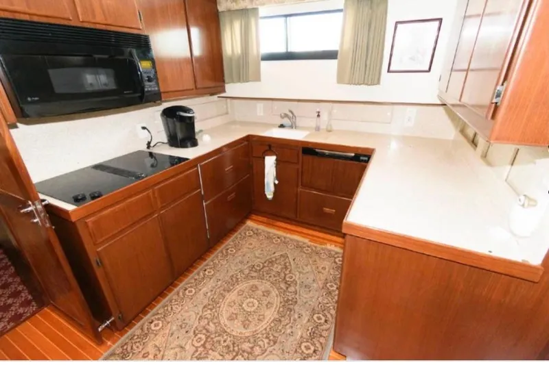  Yacht Photos Pics 1988 Hatteras 54 Motor Yacht kitchen with wooden cabinets, modern appliances, and a cozy rug.