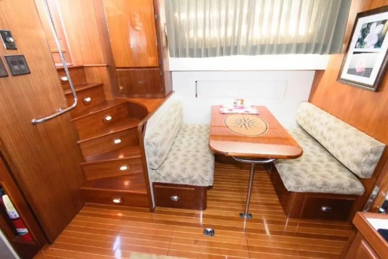  Yacht Photos Pics Interior of 1988 Hatteras 54 Motor Yacht with wooden dining area and cushioned seating.