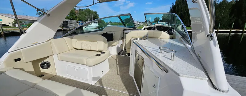 Yacht Photos Pics 2018 Regal 33 XO boat interior with beige seating and kitchenette, docked by the water.
