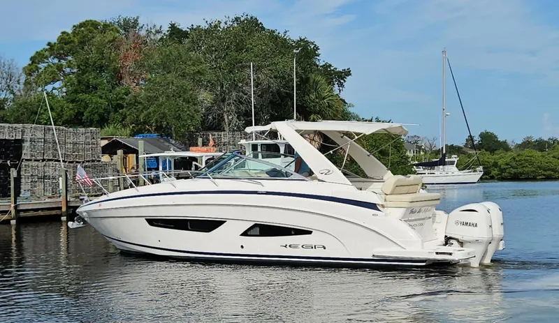  Yacht Photos Pics 2018 Regal 33 XO boat on calm water, surrounded by lush greenery and docks.