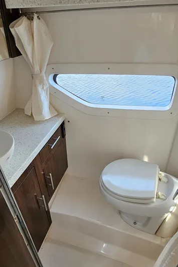  Yacht Photos Pics 2018 Regal 33 XO boat bathroom with window, toilet, and wooden cabinetry.