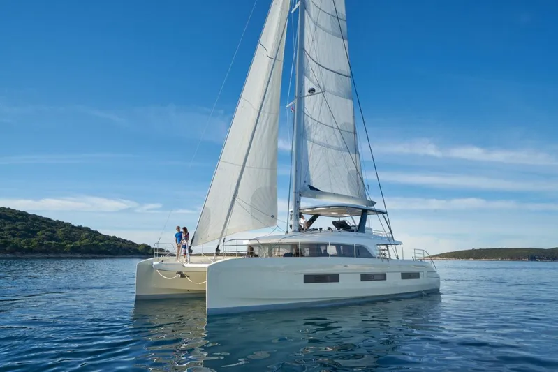 Amada Mia Yacht Photos Pics 2021 Lagoon Sixty5 catamaran sailing on calm waters under a clear blue sky.