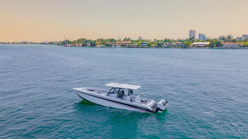  Yacht Photos Pics 2019 Nor-Tech 390 Sport boat cruising on calm waters near a city skyline.
